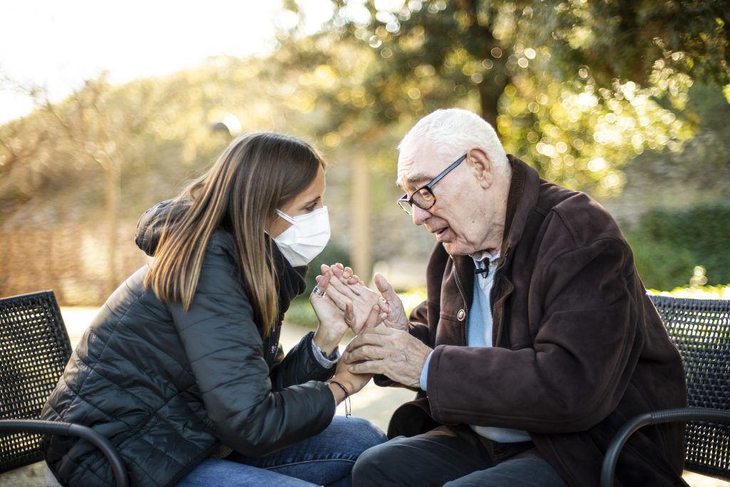 A mediator communicating through sign language, in contact with an elderly person with deafblindness